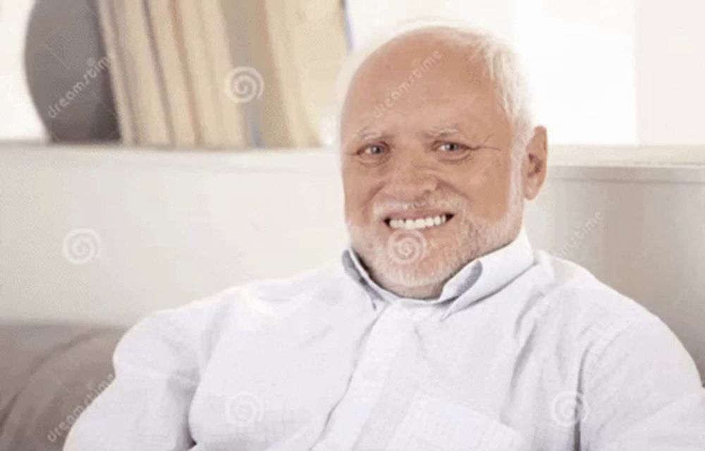 an elderly man with a beard is smiling and sitting on a couch