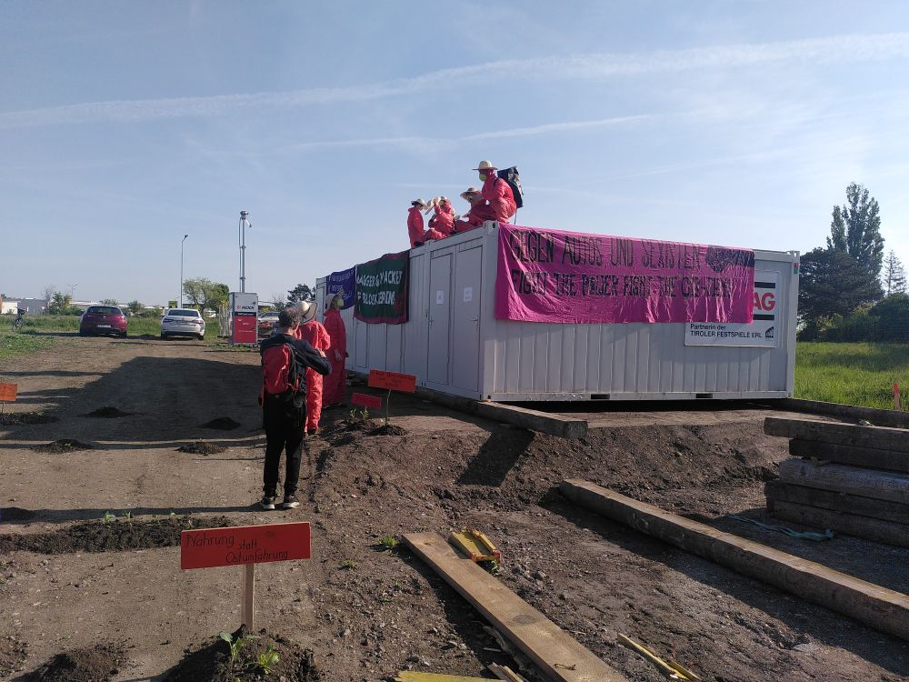 Aktivisten und Aktivistinnen in roten Anzügen Pflanzen Gemüse bei der Besetzung einer Baustelle