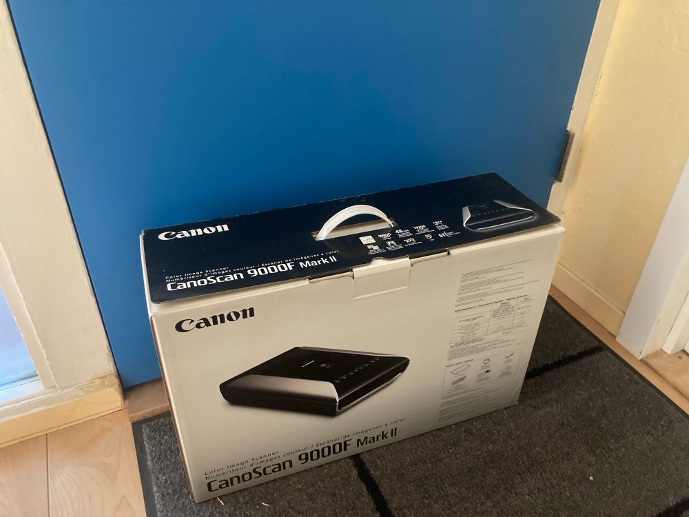 The box of a Canon scanner, in front of a blue door.