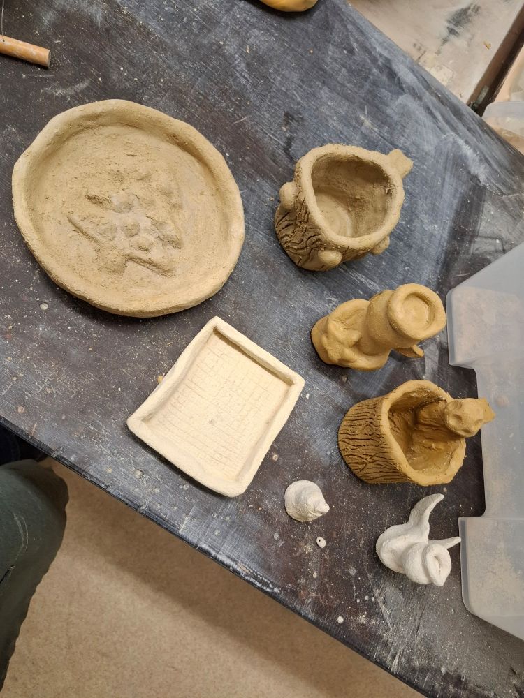Various Ceramic pieces (not fired or glazed) including two angels, two mugs, a plate, a little rectangular type of plate and a tiny bell.