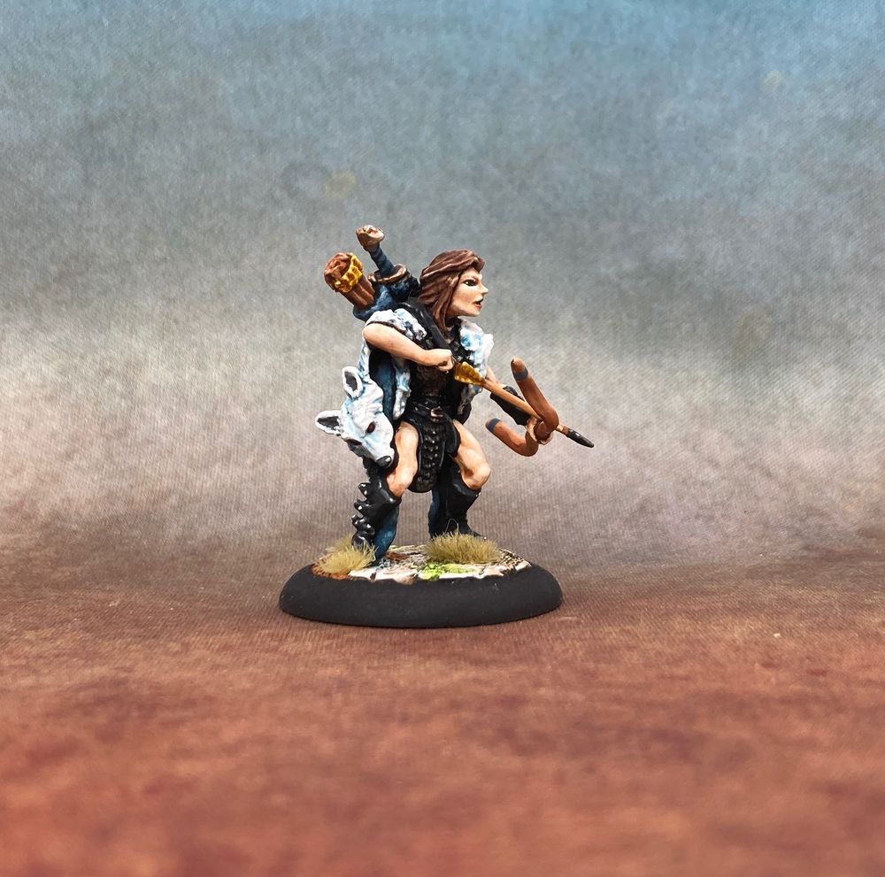Profile view of an elf in black armour and boots, clad in a white cloak and with an arrow nocked to her bow.