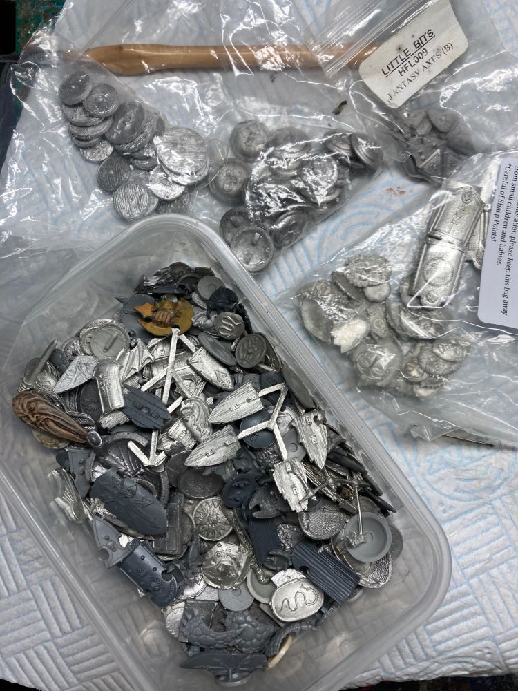 Open box containing lots of metal and plastic shields. Beside it are bags containing more shields.