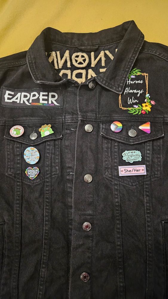A black denim jacket with Earper on the front and Heroes Always Win and an assortment of pins and badges. 