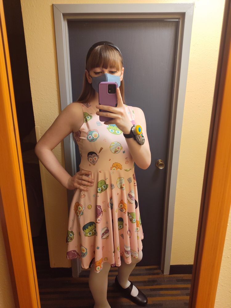 A mirror selfie. Im standing with a hand on my hip and wearing a monster mash dress and have my hair pulled back. 