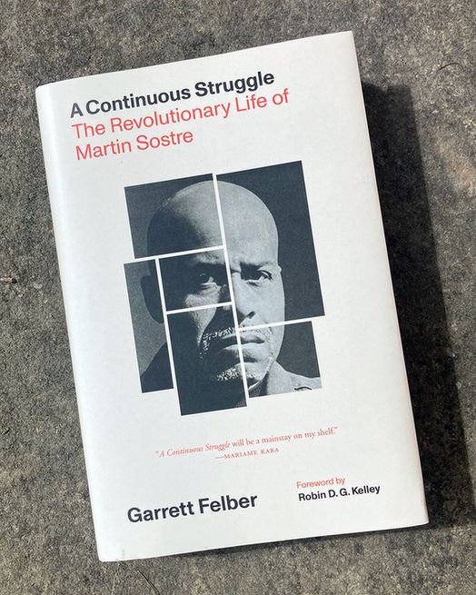 A hardcover copy of A Continuous Struggle, with a vintage-inspired cover design including a black-and-white photograph of Martin Sostre, rests against a rocky background.