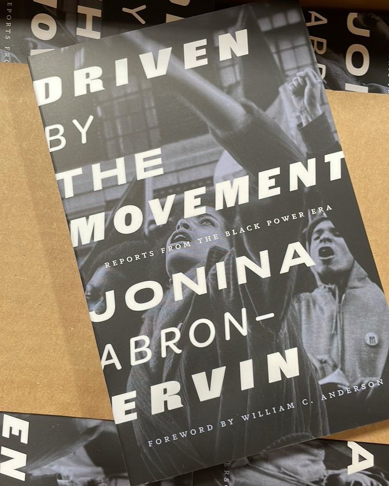 A copy of the book Driven by the Movement: Reports from the Black Power Era sits atop a box full of the same book. 