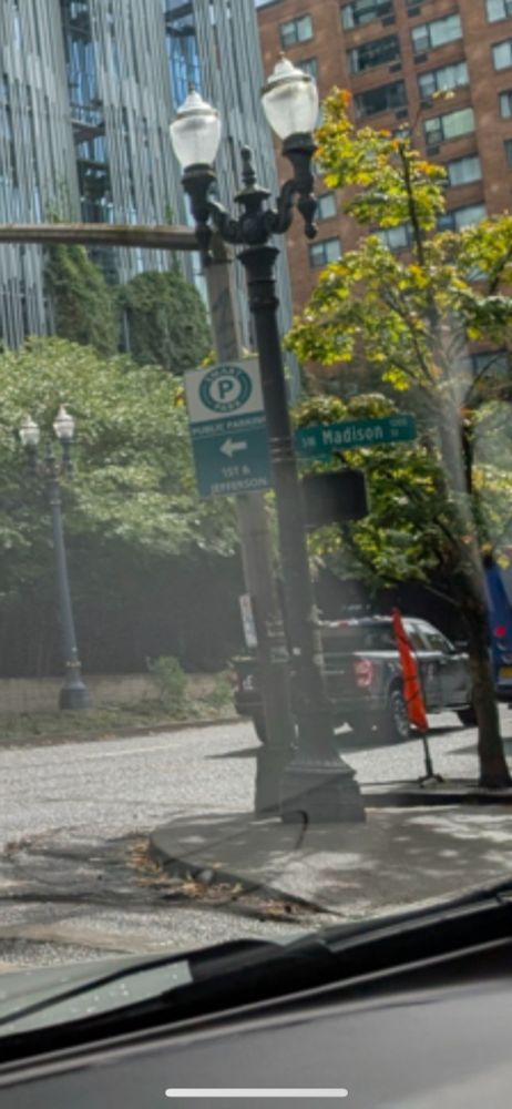 An image of a street with a red flag in a flag stand on the sidewalk. 