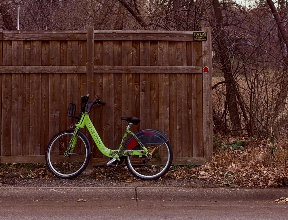 NiceRide-branded green bike leaning against a wood fence. 