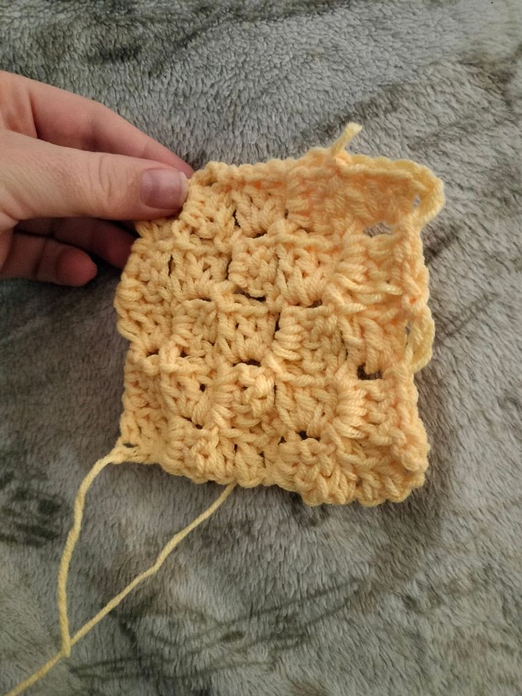 Cuadrado hecho en crochet con hilo amarillo vainilla. Consiste en 5x5 cuadrados del tamaño de la uña de un pulgar.