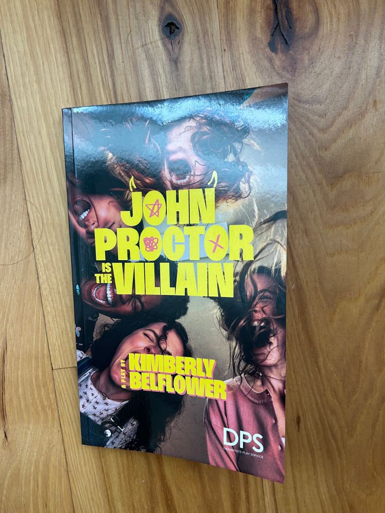 Photo of the book of the play “John Proctor is the Villain” by Kimberly Belflower. Cover art is the poster from the Broadway play, with five girls screaming. 