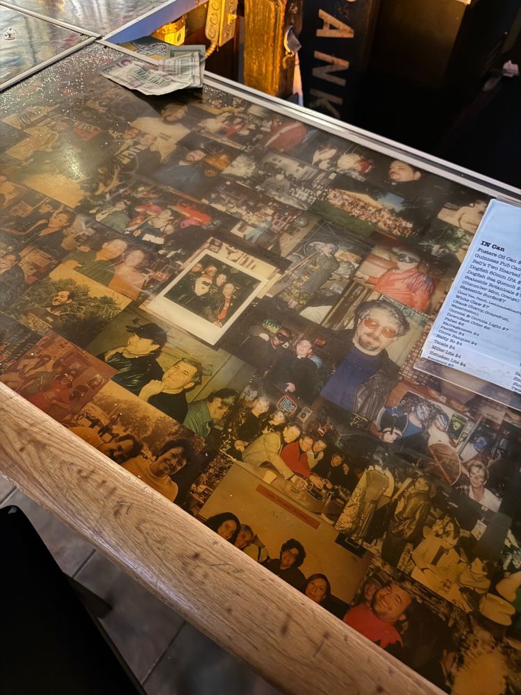 A bar counter top with Polaroids underneath 