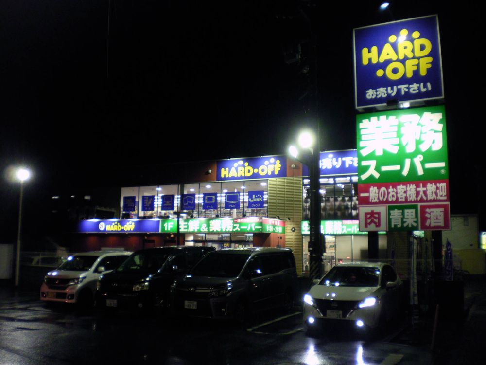 Little HardOff store above a supermarket, in the rain at night