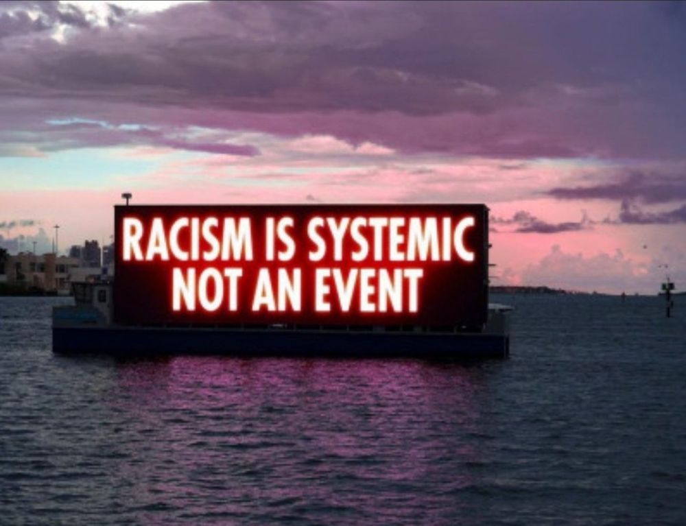 Jenny Holzer installation on a barge in the water that reads, 'Racism is Systemic Not An Event'