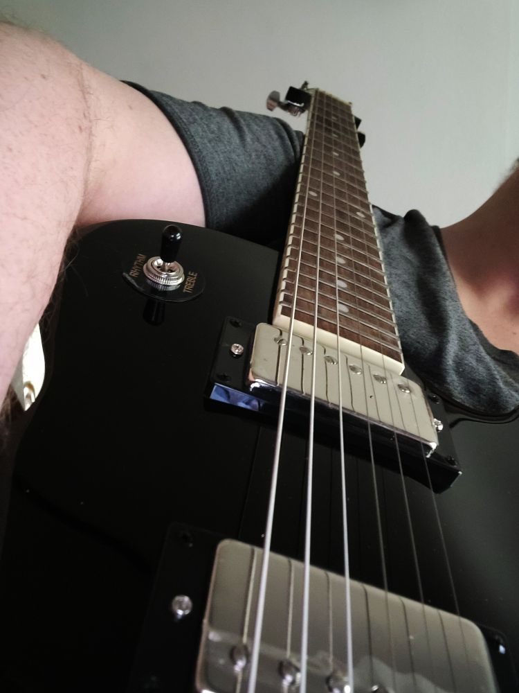 author holding an ebony epiphone les paul tribute guitar 