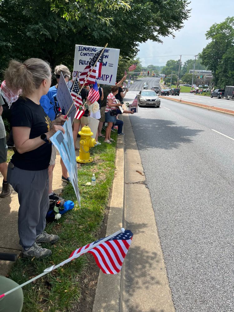 Protestors along a road in Maryland USA waving American flags and showing signs im support of the no kings day events.