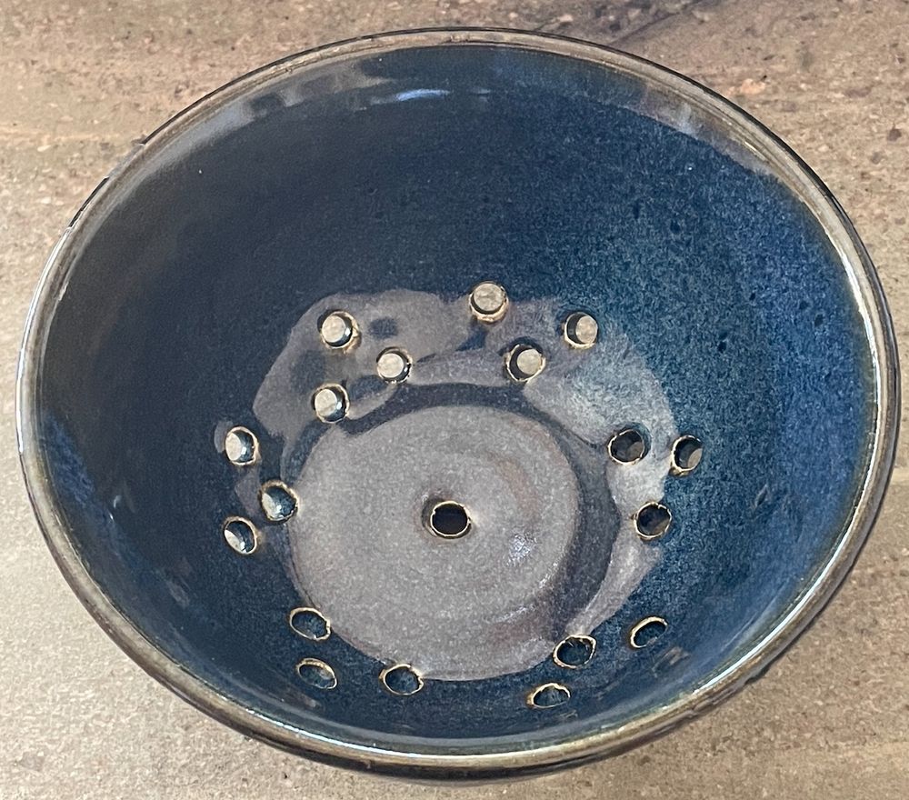 Inside of navy blue bowl showing holes for water drainage while washing berries.