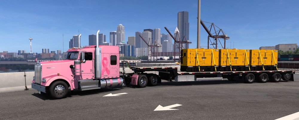 in-game photo-mode W900 flat-top cab painted ballet pink with pink ribbon made of tiny heart-shape icons on sleeper side, black-and-aluminum step-deck trailer with yellow-and-black cargo, Seattle city center in background with space needle on the left behind nose of truck. Pink ribbon for cancer awareness from optional Pink Ribbon DLC for American Truck Simulator.