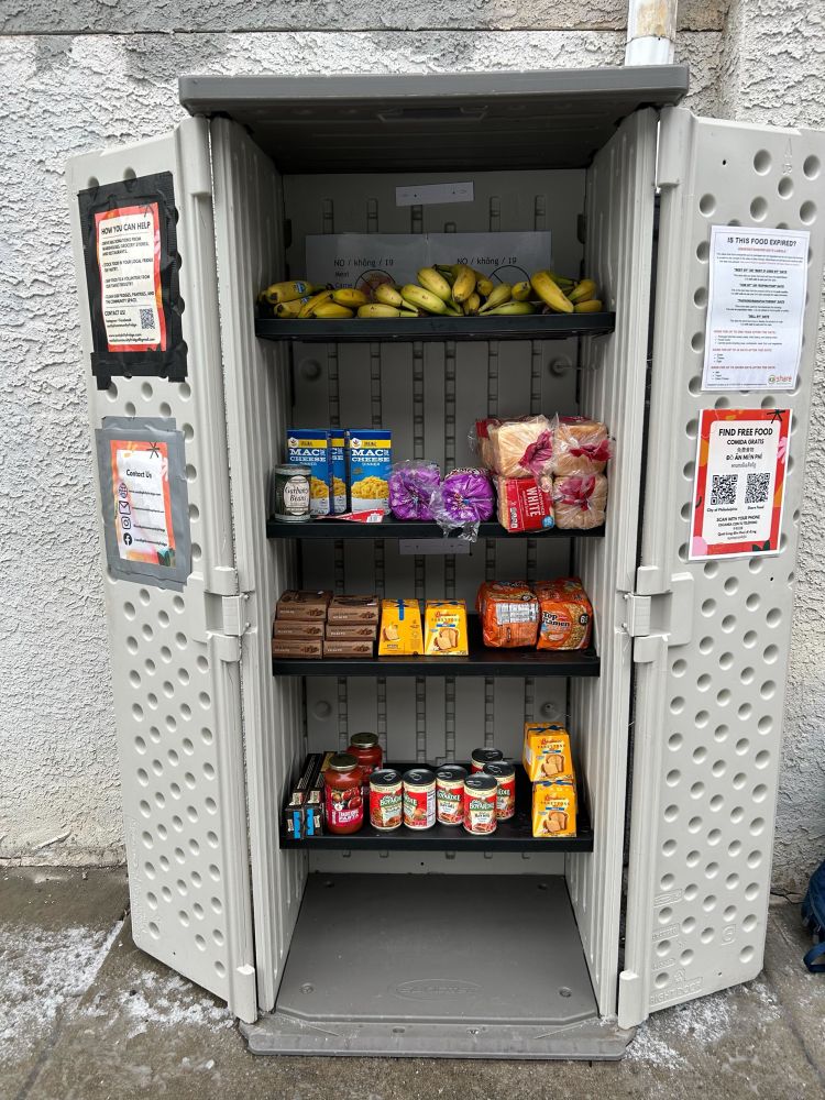 Community pantry in front of Porco’s filled with bananas, bread, pecan pie, ramen, and pasta.