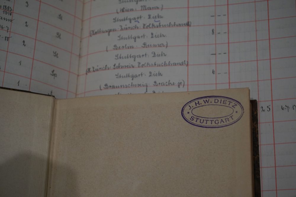 Ein Stempel in einem aufgeschlagenen Buch, es liegt auf einem Zugangsbuch.