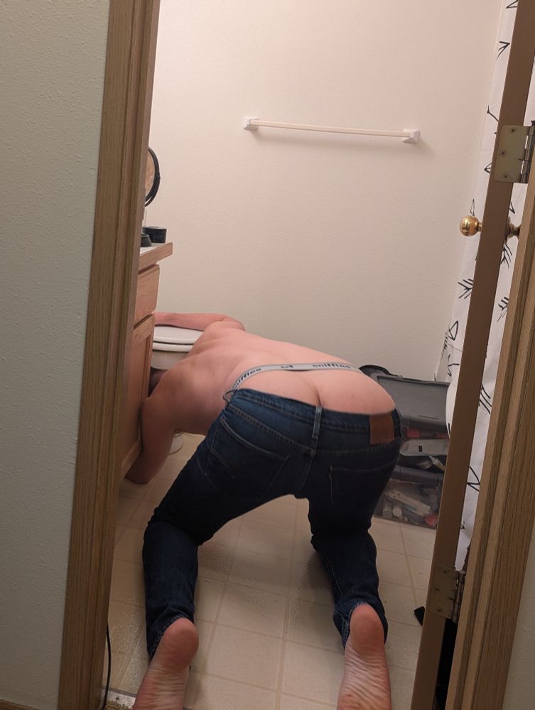 Ben bent over working under a toilet
