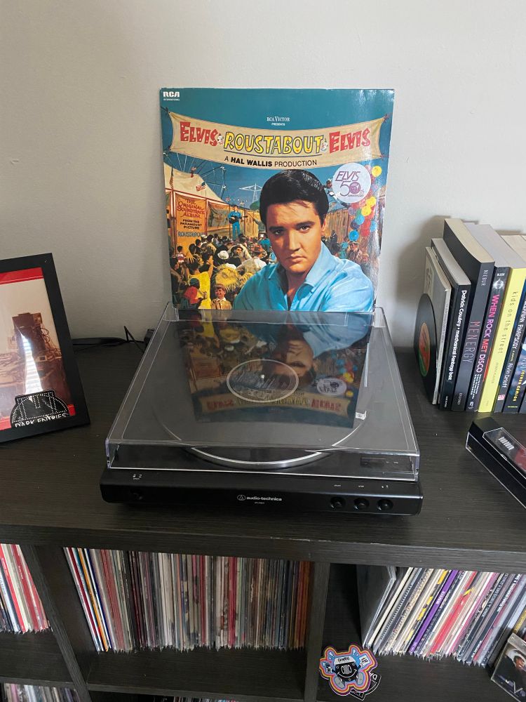 Vinyl cover sleeve of Roustabout by Elvis Presley sitting on top of a record player