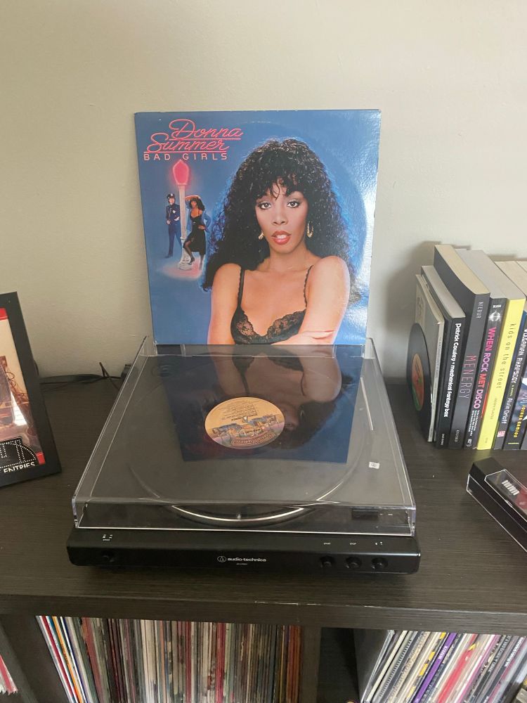Vinyl cover sleeve of Bad Girls by Donna Summer sitting on top of a record player