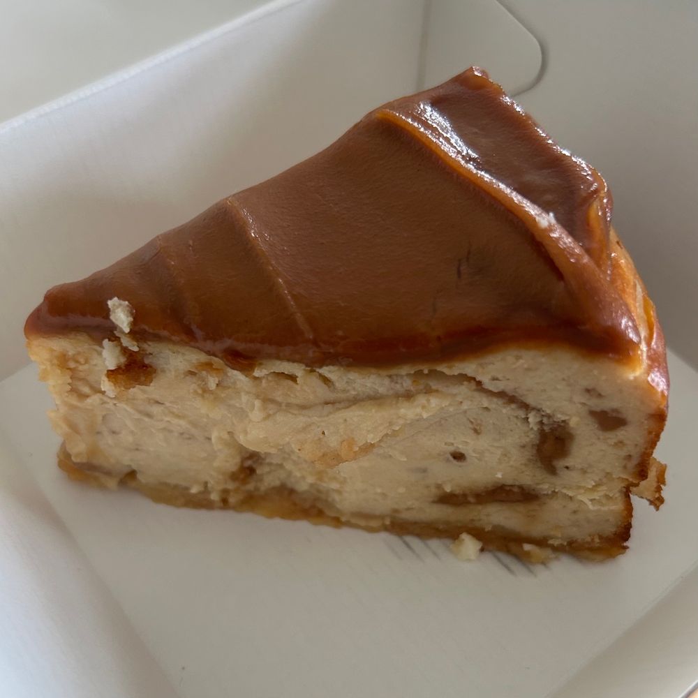Slice of cheesecake covered in caramel sauce in a box