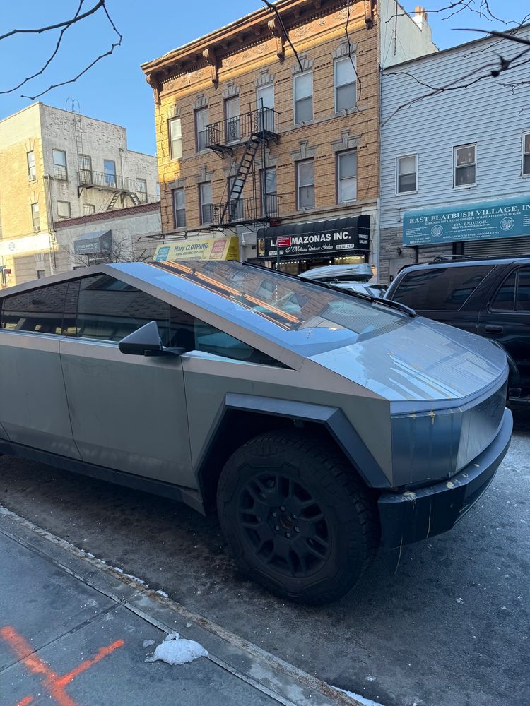 A cybertruck parked on the street with dried raw egg dripping down its front.