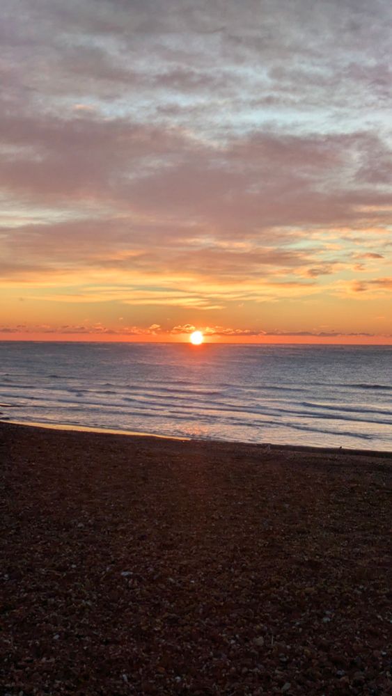 A photo of a golden sun rising over a calm, dark sea
