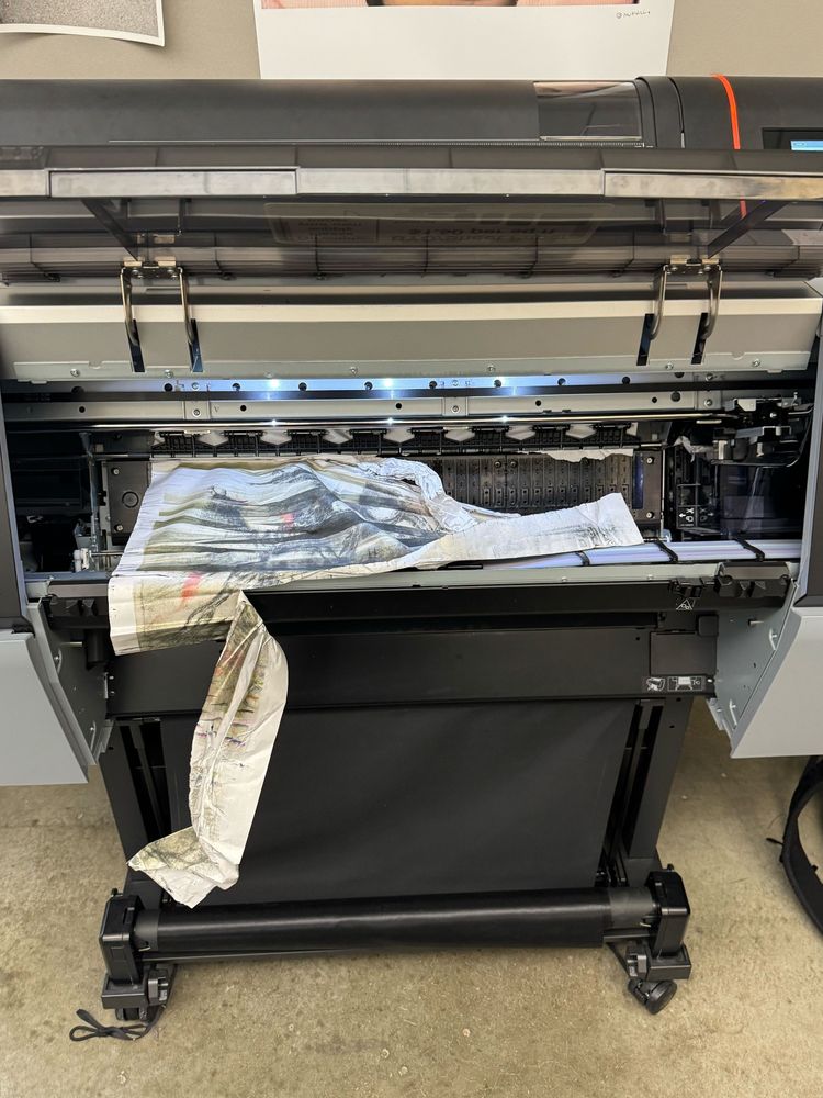 A large inkjet printer with its top open and a piece of shredded paper inside.