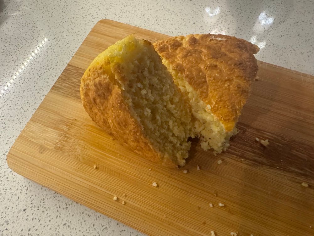 A couple wedges of fresh-baked cornbread on a cutting board. 