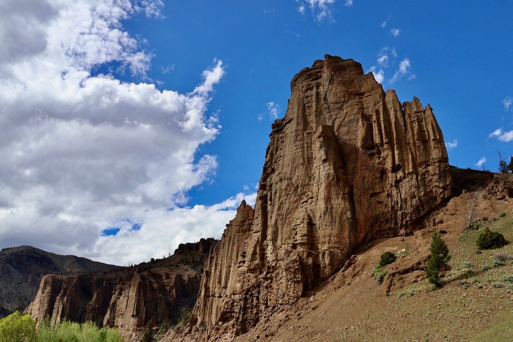 A large rock formation rising up against a partly cloudy sky.