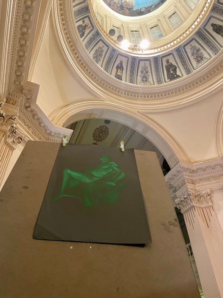 Picture of a drawing clipped to a board. The background depicts a chapel with intricately detailed pillars and crowning supporting a domed ceiling decorated with paintings of saints. 