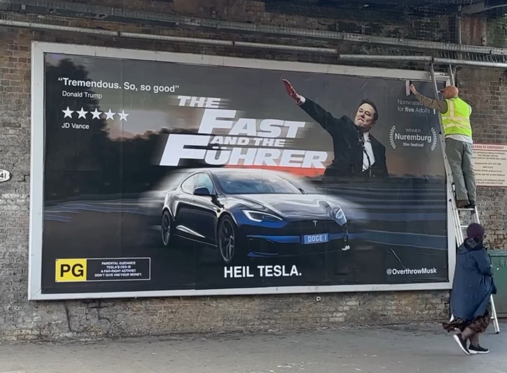 Elon Musk mit seinem umstrittenen Gruß vor einem Film Plakat: the Fast and the Führer