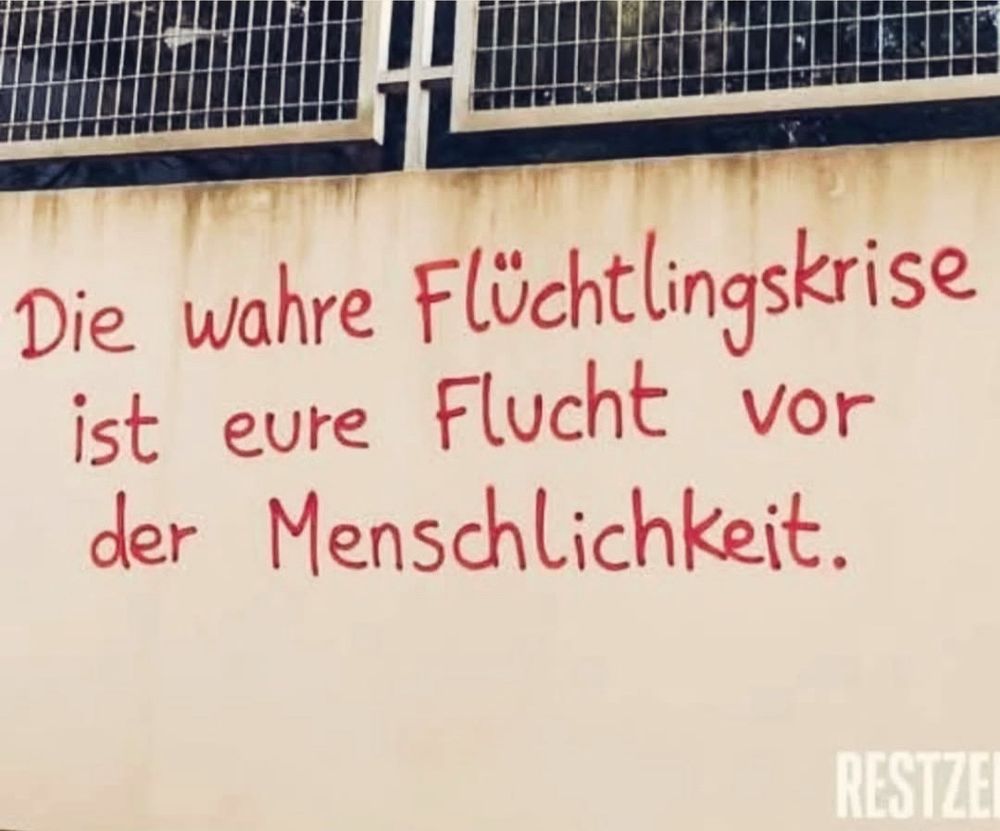 Hauswand mit Grafitti: die wahre Flüchtlingskrise ist eure Flucht vor der Menschlichkeit.