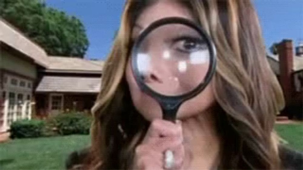 a woman is looking through a magnifying glass in front of a house .