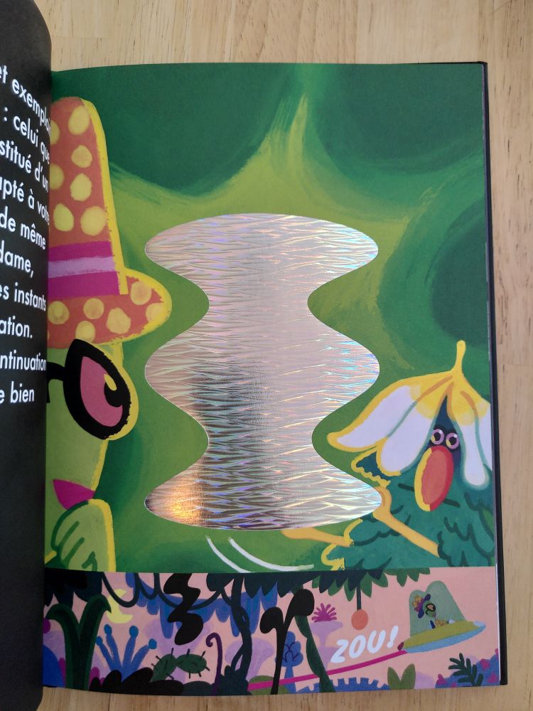 Page intérieure de l'album jeunesse Toc Toc Zinzin. On y voit une forme non-identifiée au centre, sur un papier brillant. Autour, du vert forêt avec un personnage d'OVNI sur la gauche et un être de la forêt sur la droite. En bas de la page, une vignette où l'on voit une soucoupe volante s'envoler.