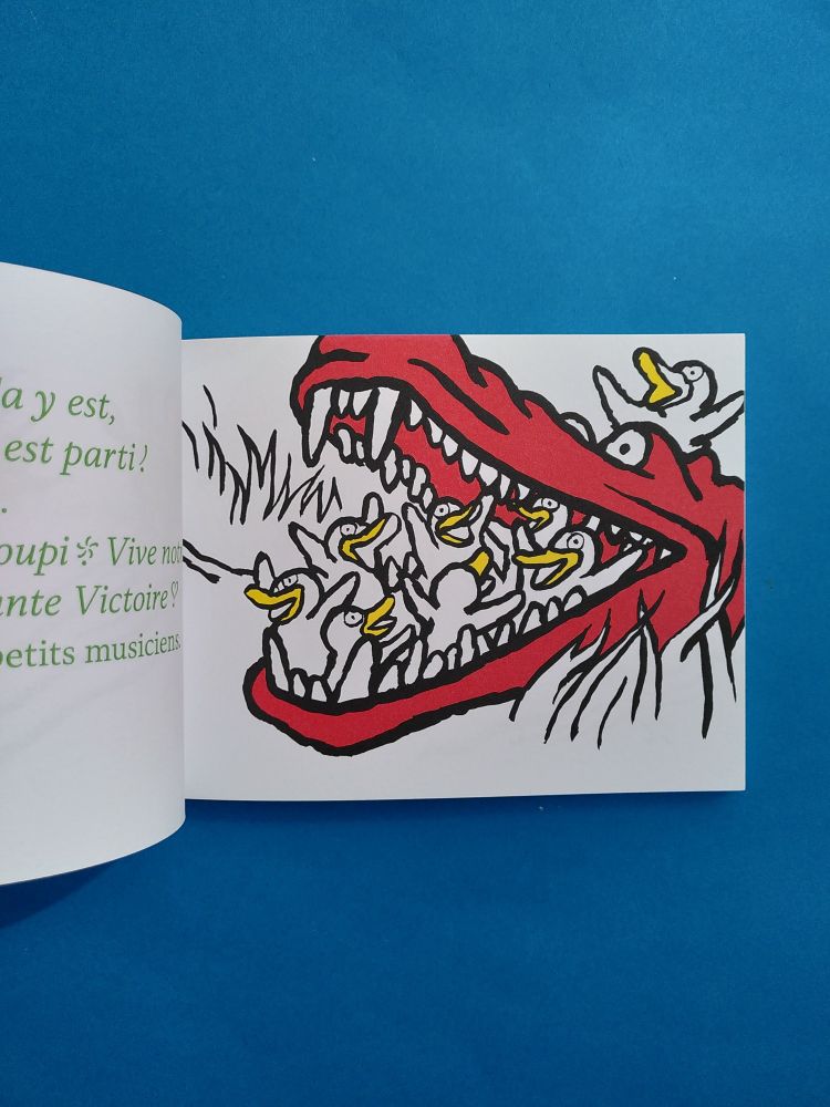 Page intérieure de L'HISTOIRE DES PETITS MUSICIENS avec un crocodile en rouge tenant dans sa gueule des poussins blancs.