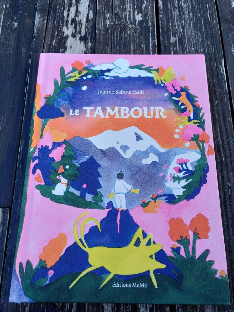 Couverture du livre Le Tambour de Jeanne Sabourault où l'on voit un enfant au milieu d'un paysage très coloré de fleurs et de montagne 