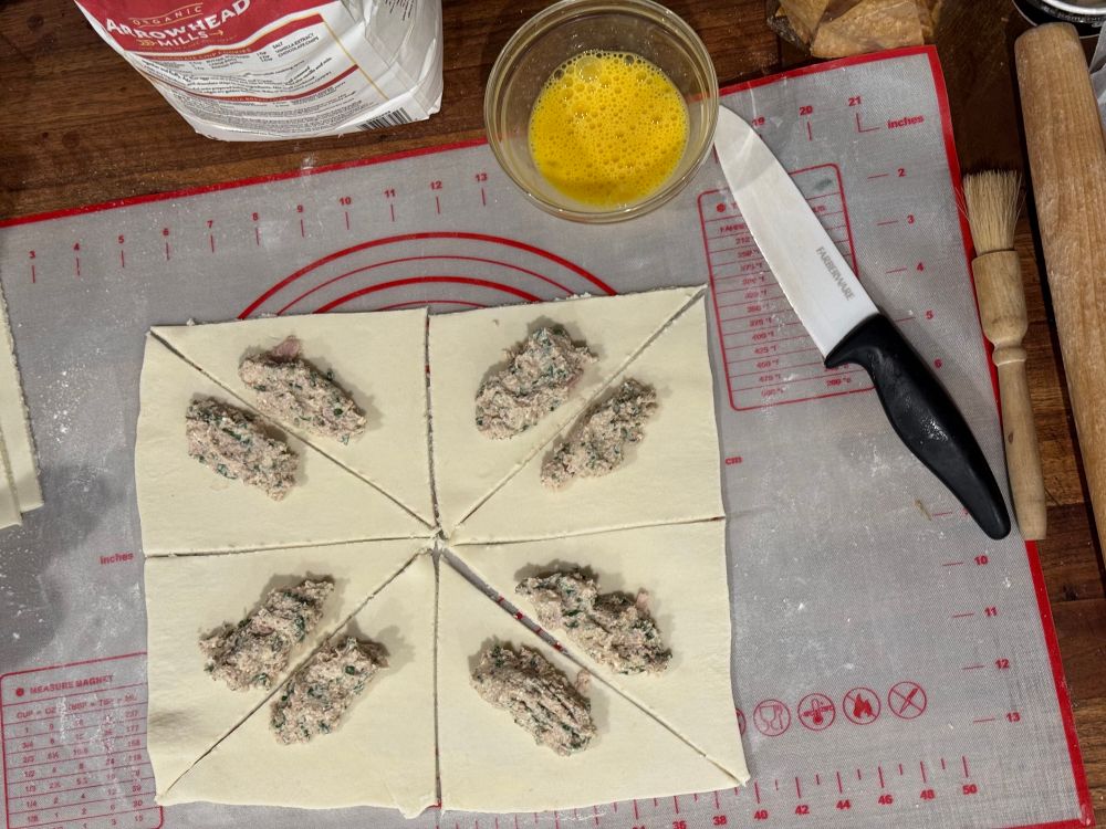 Swiss croissant jambon being made.  Filling on triangles of dough.