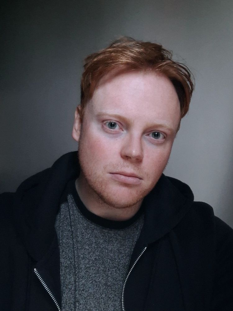 A selfie of me hiding from the storm outside wearing a warm blue hoody and a grey top