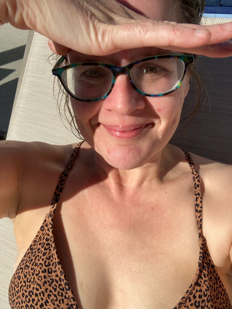 Lady with blue glasses shading her eyes while looking at the camera