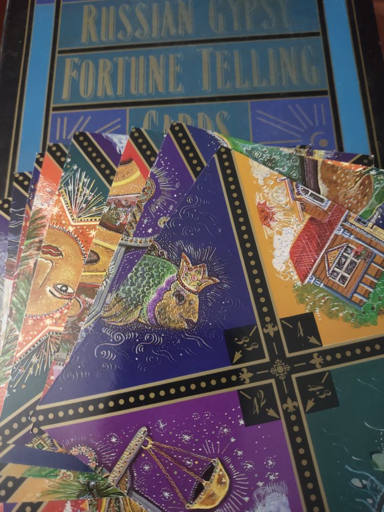 Square fortune telling cards spread out across the box that holds the cards and guide book.

Cards have four partial pictures. When lined up side by side, you look for matching pictures by rotating the cards.

How to use: 5 rows of 5 cards each. Starting with top row, look for matching pictures then go to next row, etc. Use the guide book to find appropriate meaning.