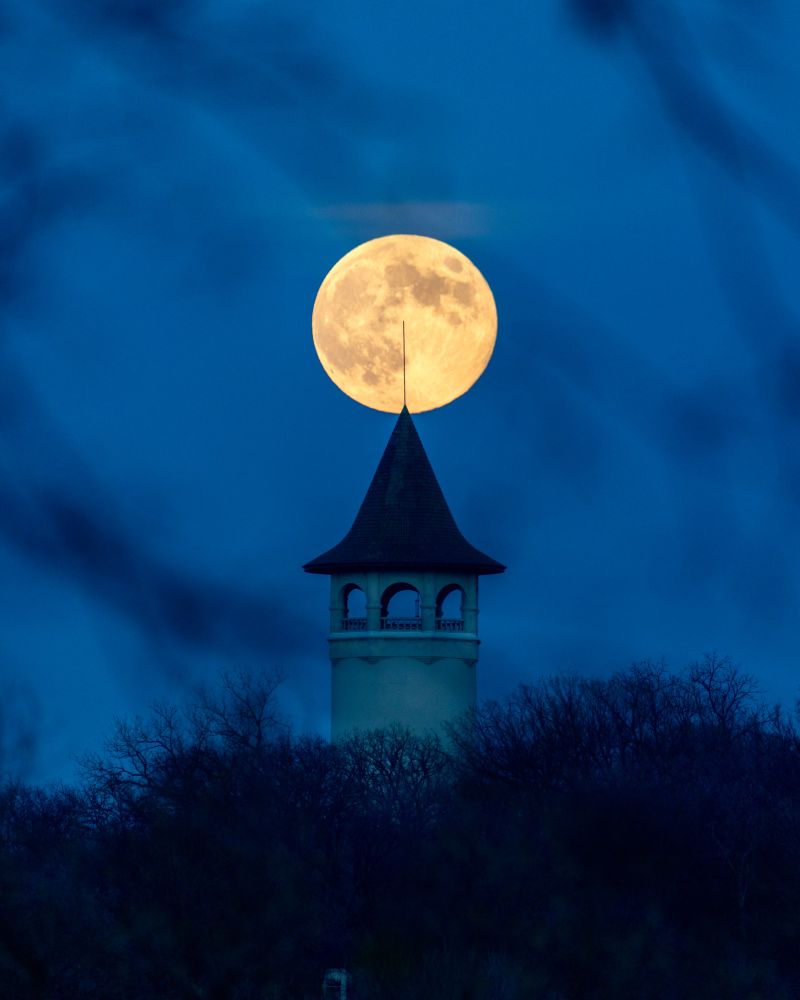 A large full moon is framed above a conical water tower