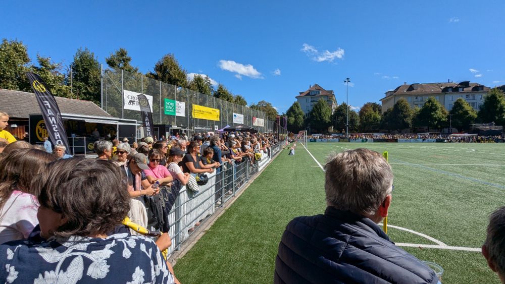 Fussballfeld mit vielen Zuschauer:innen.