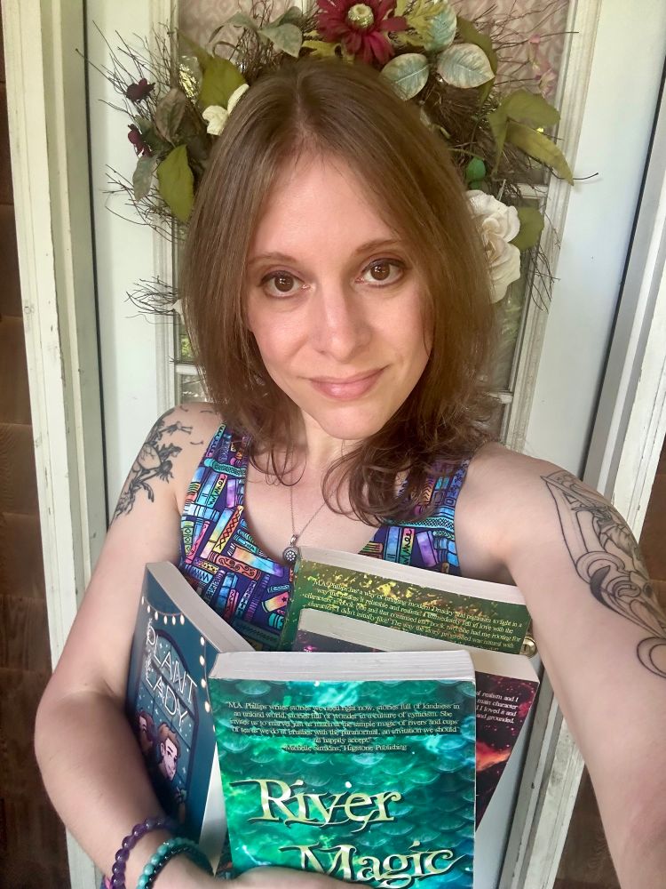 A woman stands in front of a doorway holding four books. 