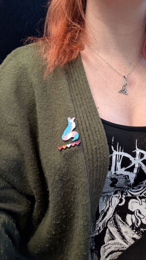 Picture of a fox pin badge in trans pride flag colours. 