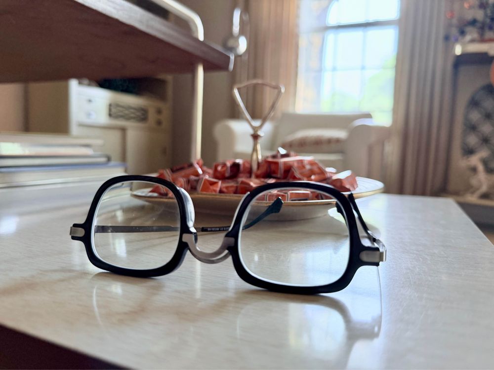 A pair of glasses on a white table next to a plate of red candies.
