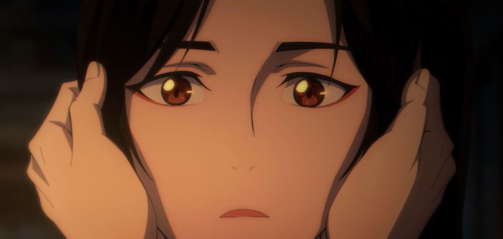 An image of San Lang (Hua Cheng) from the TGCF donghua Season 1 special episode (episode 12). The image shows San Lang's face. His eyes are shining and he looks surprised (and adorable). Xie Lian has grabbed his face and you can see his hands wrapped around San Lang's head, covering San Lang's ears and part of his hair.