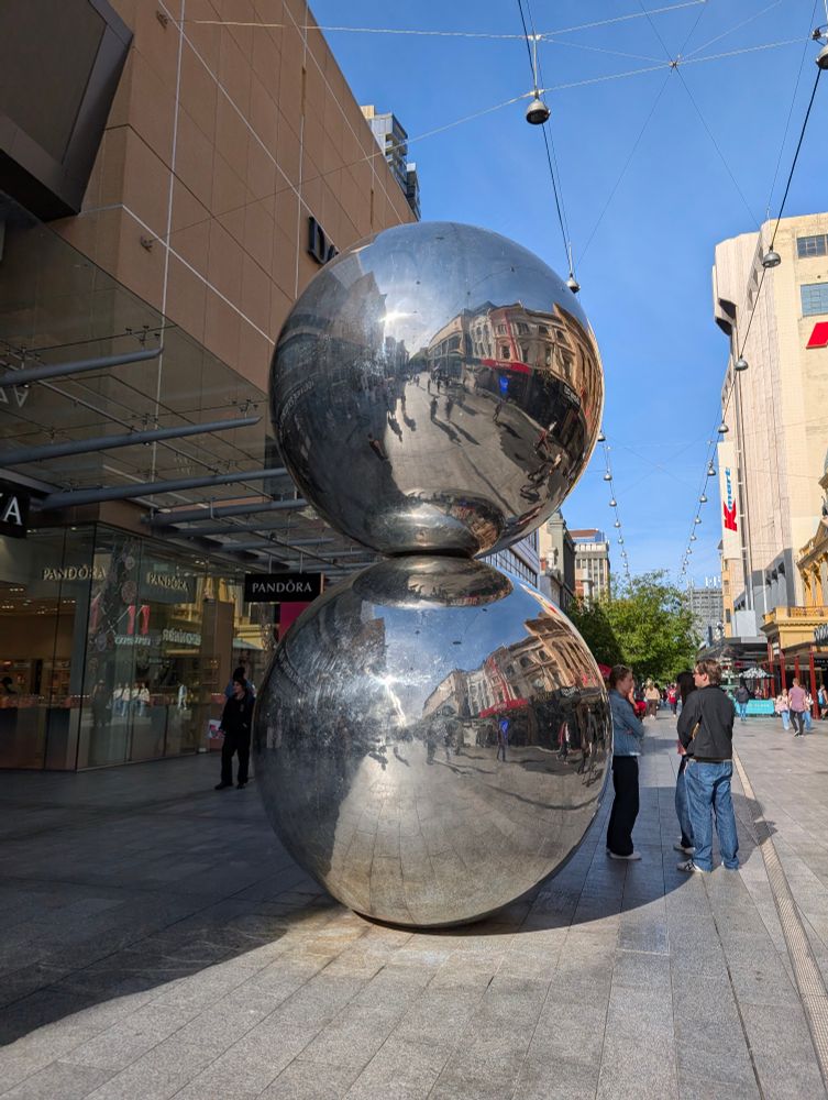 A large art piece of two metallic spheres, stacked vertically 